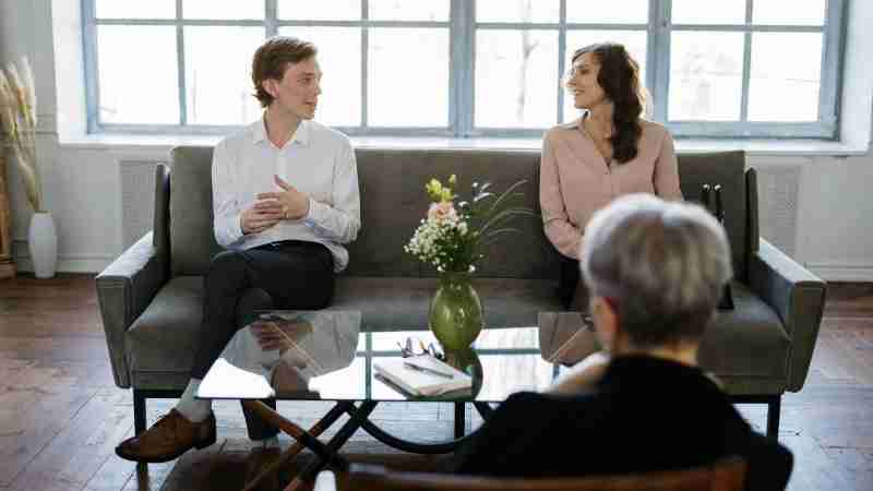 Couple engaged in a therapy session with a counselor in a loft setting., tags: terapia di - pexel