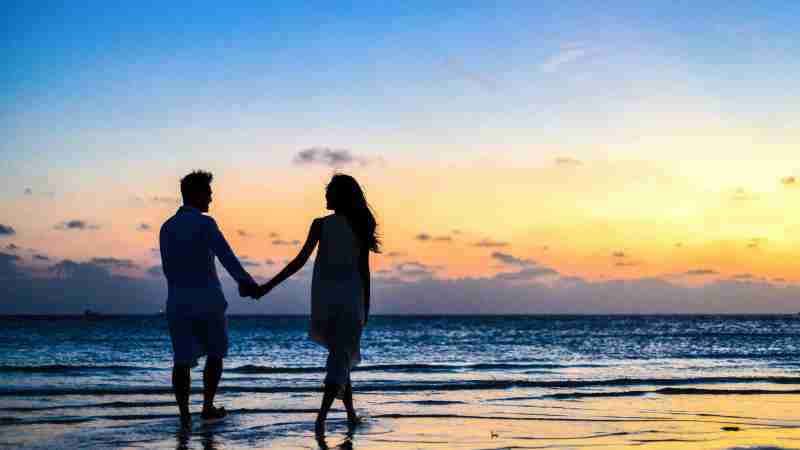 A romantic couple walks hand in hand on a tropical beach at sunset, enjoying a serene moment together., tags: il partner migliore - pexel