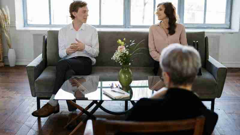 Couple engaged in a therapy session with a counselor in a loft setting., tags: la terapia di - pexel